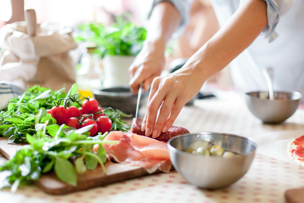 A woman hand cuts vegetables on table on wooden cutting board. 