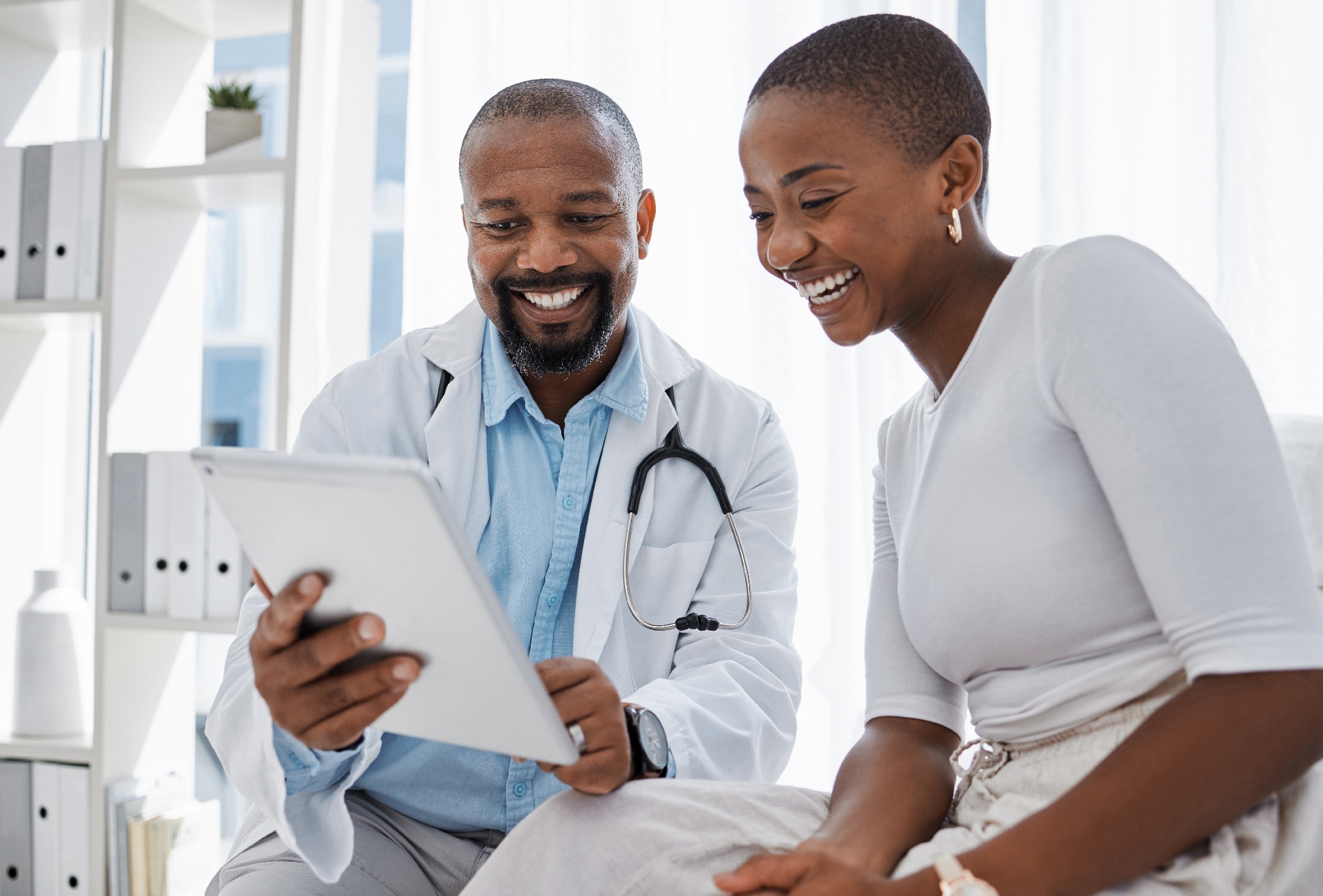 A male doctor shows a female patient the Pyx Health app on an iPad.