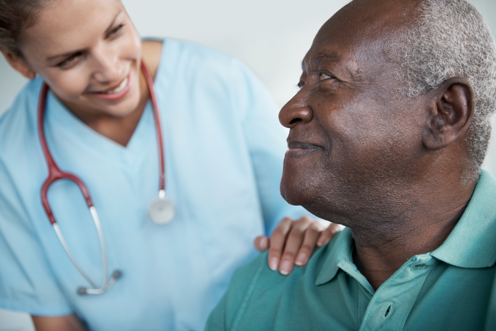 Female nurse comforting male patient at health care facility.